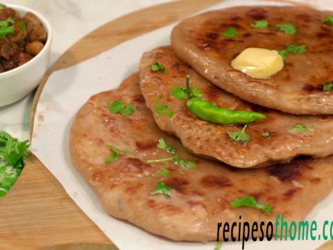 aloo paratha place on wooden food plater topping with butter and gren chili