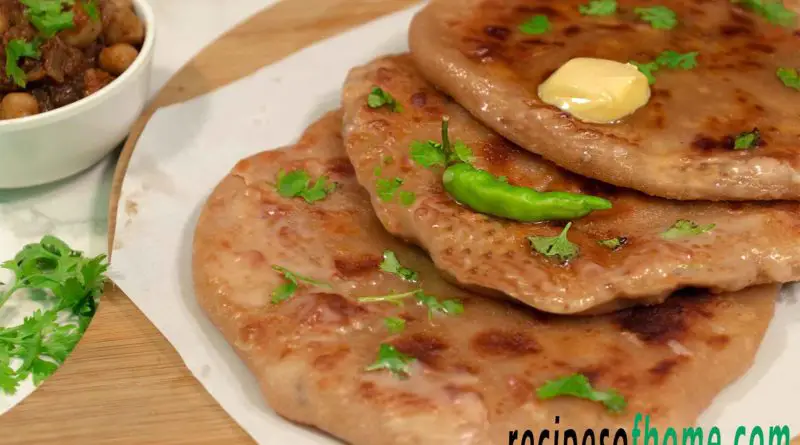 aloo paratha place on wooden food plater topping with butter and gren chili
