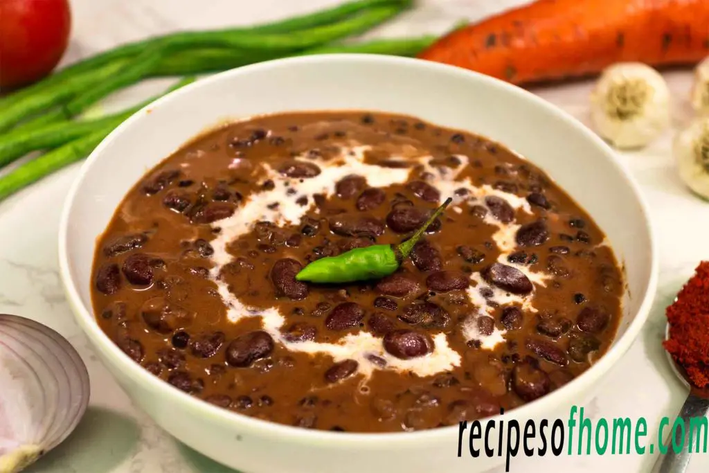dal makhani served in a white bowl garnish with cream and green chili