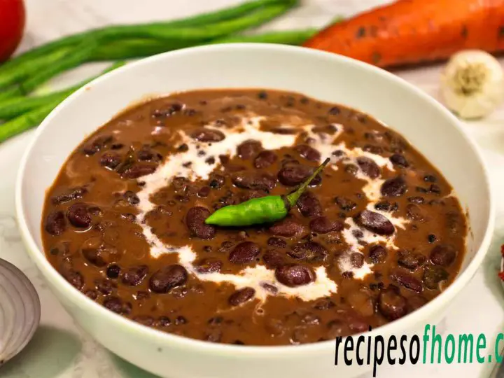 dal makhani served in a white bowl garnish with cream and green chili