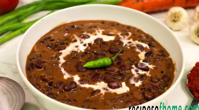 dal makhani served in a white bowl garnish with cream and green chili