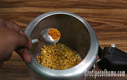 pour soaked chana dal along with turmeric powder in a pressure cooker