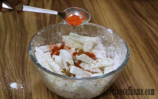 coat blanch potatoes with cornstarch , red chilli powder , salt , black pepper and pinch of yellow food color