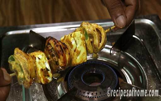 cook paneer tikka on gas stove by holding hand
