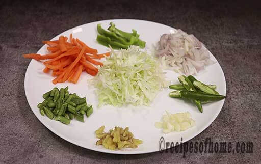 chop onions,french beans, ginger garlic, cabbage, slice carrots, capsicum on plate